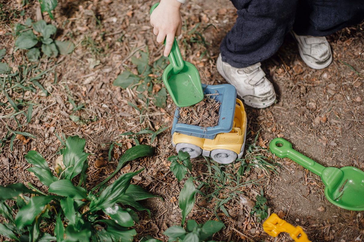 A child playing outdoors with toy trucks